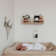 a baby laying on top of a bed next to a shelf with potted plants