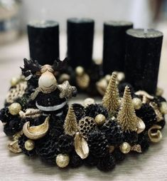 black and gold christmas wreath with candles on the table in front of two pillar holders