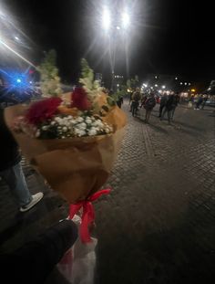 a bunch of flowers that are sitting on the ground in front of some people at night