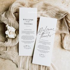 two wedding programs with calligraphy on them sitting next to a bouquet of white flowers