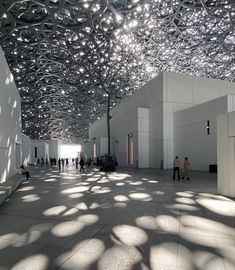 people are walking around in an open space with lots of light coming through the ceiling