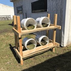 three white buckets are stacked on a wooden rack