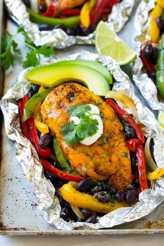 chicken with black beans, peppers, avocado and limes on tin foil