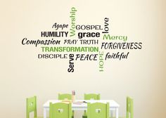 a dining room table with green chairs and a wall decal in the shape of words