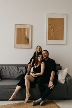 a man, woman and child sitting on a couch in a living room with white walls