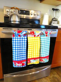 three colorful kitchen towels hanging from the oven