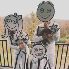 two people are standing on a porch with paper cutouts in the shape of faces