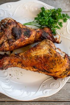 two chicken legs on a white plate with parsley