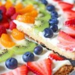 fruit pizza with slices cut out sitting on a table