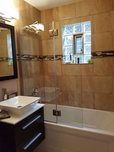 a bathroom with a sink, mirror and bathtub next to a window in the wall