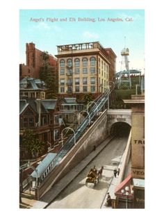 an old postcard shows people riding horses and carriages on the tracks in front of buildings