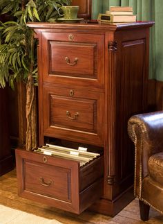 a brown chair sitting next to a tall wooden cabinet with drawers on it's sides