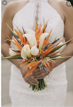 a woman holding a bouquet of flowers in her hands and wearing a white dress with orange accents