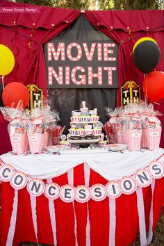 a circus themed movie night party with red and white striped tablecloths, balloons, and cake