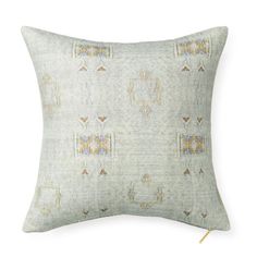 a light green pillow with an embroidered design on the front and back, along with gold trimmings