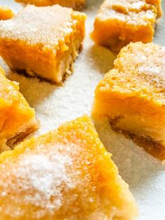 several pieces of dessert sitting on top of a white paper towel covered in powdered sugar