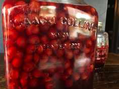 a jar filled with red cherries sitting on top of a wooden table