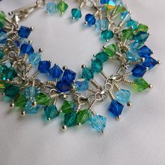 This is a handmade whimsical beaded crystal bracelet.  The chain is silver plated, the headpins are sterling and the crystals are Preciosa. The crystals are 4 different yet complimentary colours (navy, light blue, teal and green).  The crystals dangle and move with every movement and create a fun shimmer on the wrist.  This bracelet marries elegance and easy going together. Handmade Blue Crystal Bracelet, Blue Beaded Crystal Bracelet In Sterling Silver, Blue Beaded Sterling Silver Crystal Bracelet, Handmade Blue Sterling Silver Charm Bracelet, Dark Blue Bracelet, Bracelet With Ring, Complimentary Colours, Teal And Green, Complimentary Colors