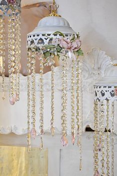 a chandelier hanging from the ceiling with flowers and pearls attached to it's sides