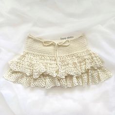 a crocheted white skirt with ruffles on the bottom is laying on a bed