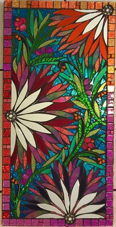 a stained glass panel with flowers and leaves on it's side, hanging from a wall