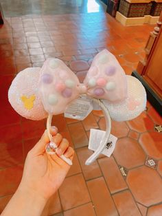 a person is holding up a minnie mouse ears headband with bubbles and bows on it