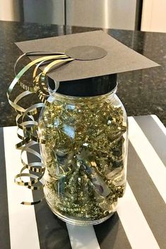 a graduation cap sits on top of a jar filled with confetti and streamers