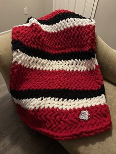 a red and white striped blanket sitting on top of a couch next to a pillow