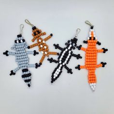 three beaded ornaments are arranged on a white surface, one is orange and the other is black