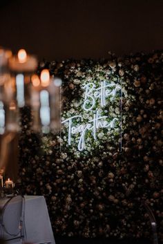 the wedding sign is surrounded by flowers and candles in front of a wall with greenery