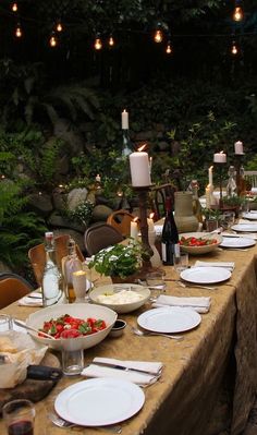 a long table is set up with plates and wine bottles for an outdoor dinner party