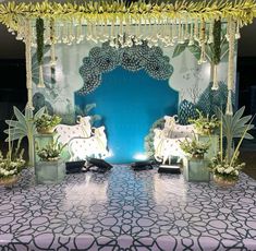 an elaborate stage set up for a party with white horses and plants on the floor