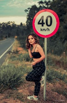 a woman standing next to a 40 km / h sign on the side of a road