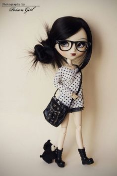 a doll wearing glasses and holding a black purse with her hair in the air, standing next to a wall