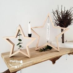 three wooden stars on a table with flowers and candles in the middle one has a candle holder