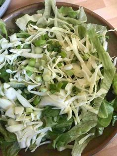 a salad with lettuce and onions in a bowl on a wooden table top