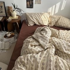 an unmade bed in a room with pictures on the wall and other items around it