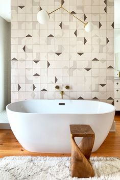 a white bathtub sitting on top of a wooden floor next to a wall mounted mirror