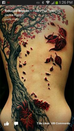 the back of a woman's body with red leaves on it and a tree