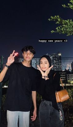 a man and woman standing next to each other in front of a city at night