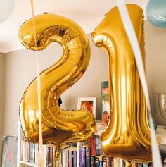 the number twenty two balloons are in front of bookshelves