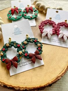 three christmas wreaths are sitting on top of a wooden table next to other ornaments