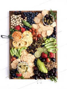 a wooden platter filled with different types of snacks and fruit on top of it