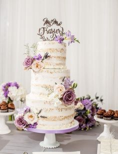 a white wedding cake with purple flowers on top