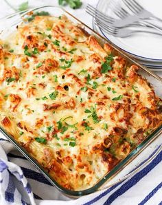 a casserole dish with cheese and vegetables in it on a blue and white towel