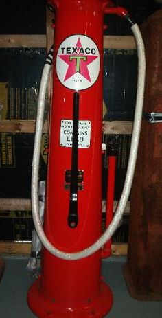 a red gas pump sitting on top of a table next to a bookshelf