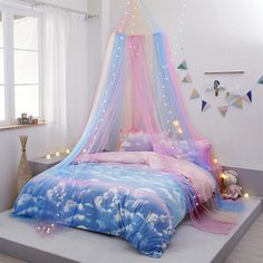 a bed with pink, blue and white bedspread on top of it next to a window