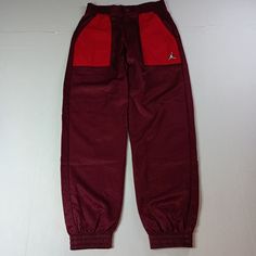 Elevate Your Activewear Collection With These Nike Air Jordan Joggers In Cherrywood Red. Designed For Women's Size Xs, These Pants Feature A Comfortable Elastic Waist And Tapered Leg Style, Perfect For A Variety Of Activities Including Gym Training, Yoga, And Running. The Drawstring Closure Ensures A Secure Fit While The Colorblock Pattern Adds A Touch Of Style. Crafted From 100% Nylon, These Pants Are Easy To Care For With Machine Washable Garment Care. The Nike Brand Represents Quality And Per Nike Joggers Red, Jordan Joggers, Casual For Work, Nike Brand, Gym Training, Nike Pants, Nike Air Jordan, Track Pants, Air Jordan