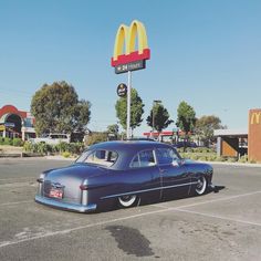 an old car parked in front of a mcdonald's