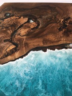 an aerial view of the ocean with waves crashing on it's shore and a piece of wood in the middle